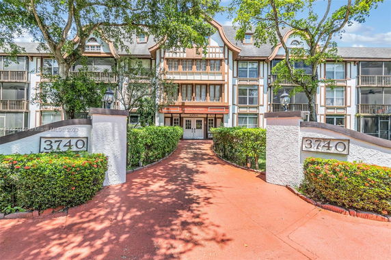 Front view of a multi-story residential building with a distinctive entrance path and greenery.