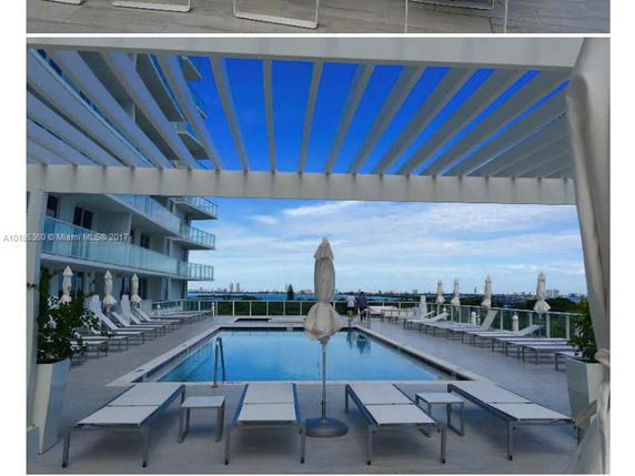 Rooftop area of a building featuring a swimming pool with surrounding lounge chairs and covered areas.