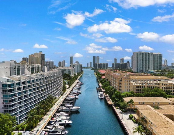 Aerial view of an urban area with multi-story buildings and a waterway lined with boats.