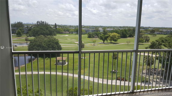 View from a balcony overlooking a golf course and surrounding greenery.