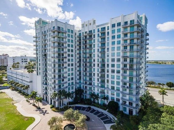 Front view of a multi-story residential building with numerous balconies overlooking a body of water.