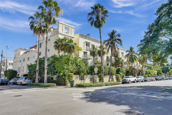 Front view of a multi-story building with balconies and palm trees.