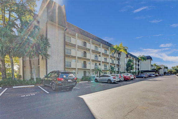 Front view of a multi-story residential building with parking area.