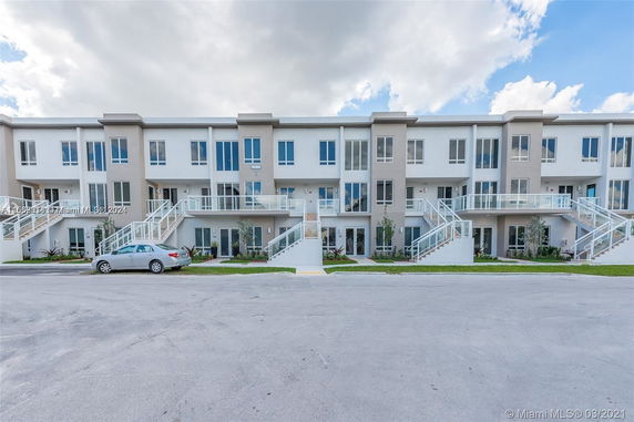 Front view of a multi-story residential building with individual entrances and staircases.