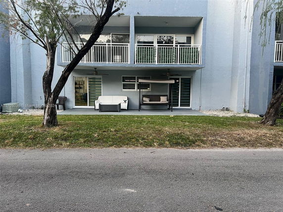 Front view of a building with balconies and a ground-level patio.