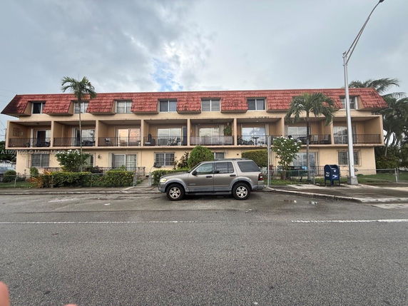 Front view of a three-story residential building with red roof accents and balconies.