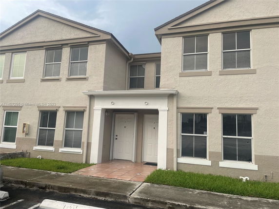 Front view of a two-story townhouse with a beige exterior and multiple windows.
