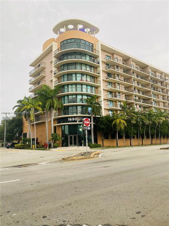 Front view of a multi-story residential building with balconies and a rounded corner.