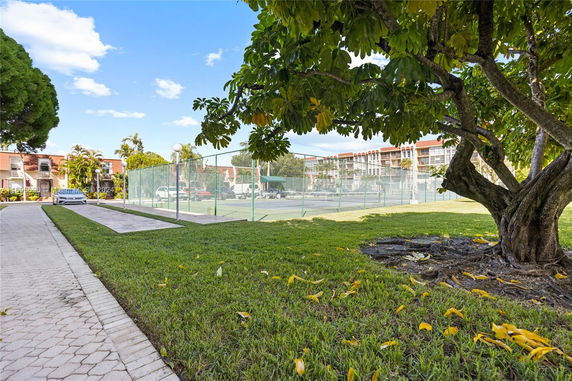 Tennis court surrounded by trees and buildings.