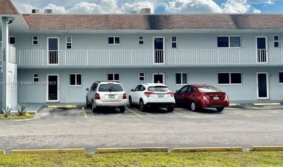 Outdoor parking area in front of a two-story building.