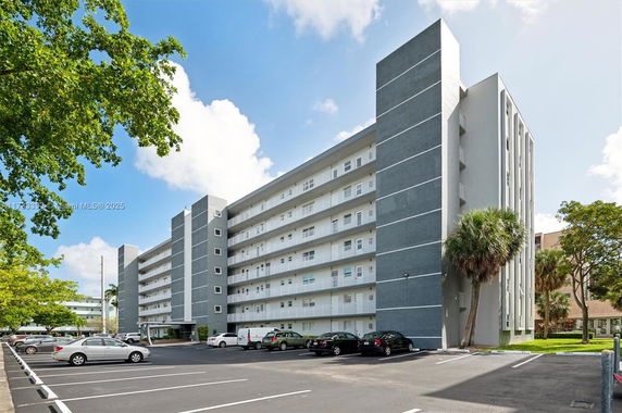 Front view of a multi-story building with adjacent parking area.