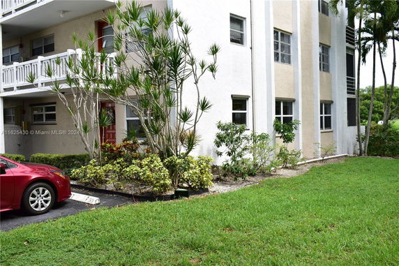 Front view of a multi-story building with balconies and surrounding greenery.