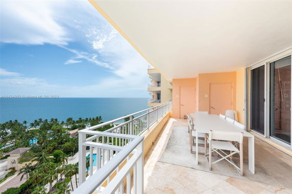 Wide-angle view from a balcony overlooking the ocean and palm trees.