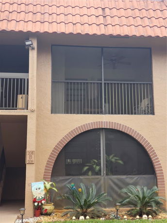 Front view of a building with a red tiled roof and screened balconies.
