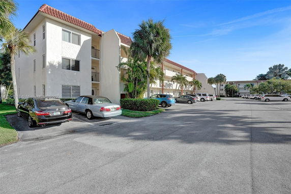 View of an apartment complex with a parking area in the foreground.