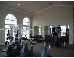 Interior view of a gym with exercise equipment and large windows.