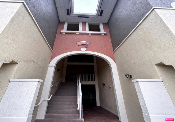 Entrance view of a building with an archway and stairway leading to an upper level.