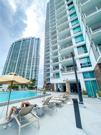 High-rise buildings with a swimming pool and lounge chairs in the foreground.