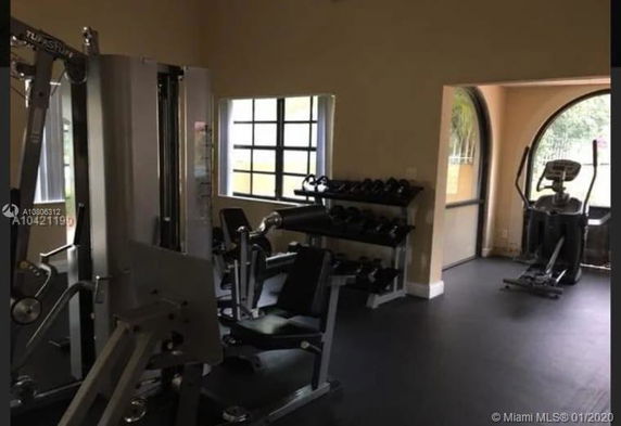 Indoor gym area with exercise equipment and weights.