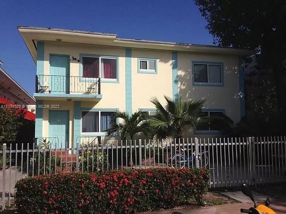 Front view of a two-story house with a balcony and a fence.