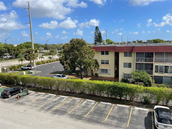 Parking area next to a two-story residential building with a red roof.