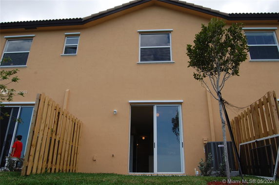 Rear view of a two-story house with sliding glass doors and fenced yard.