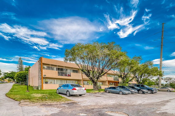 Front view of a two-story apartment building with a parking area.