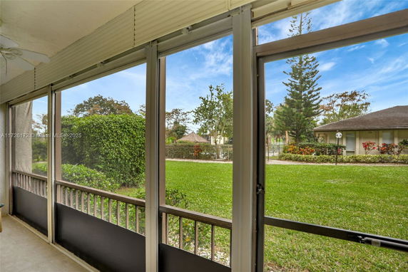 View from a patio showing a grassy yard and nearby houses.