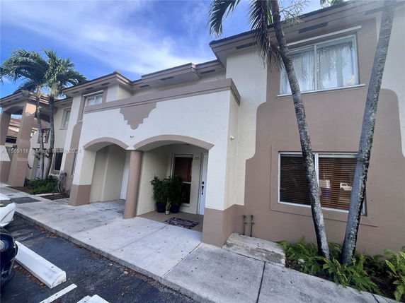 Front view of a two-story house with a partial arch design and beige color scheme.