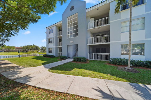 Front view of a three-story apartment building with balconies and white railings.
