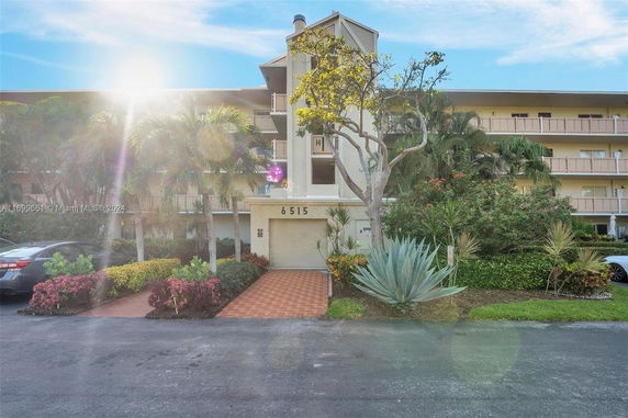 Front view of a multi-story building with balconies and lush landscaping.