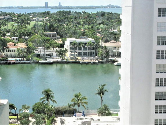 View of waterfront residential area with palm trees and buildings.
