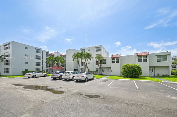 Front view of a multi-story residential building with a parking area in front.