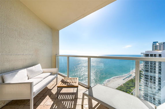 Balcony with seating overlooking the ocean and beach.