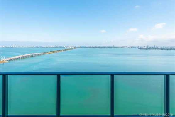 Panoramic view of a coastal area with a clear blue sky and turquoise water, seen from a high vantage point.