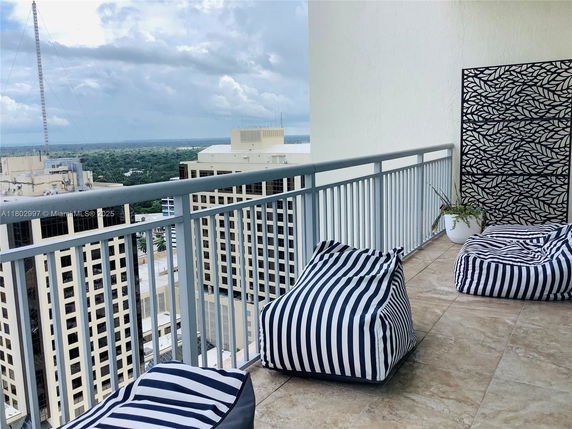 Balcony view with striped bean bags overlooking buildings and landscape.