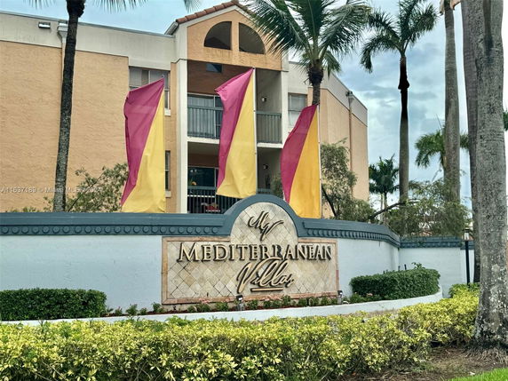 Front view of a multi-story building with balconies and colorful banners in front.