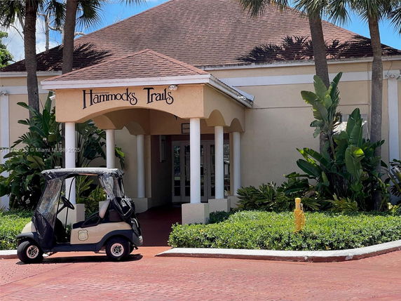 Front view of a building with a covered entrance and a golf cart parked outside.