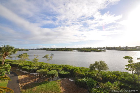 View of a body of water with trees and greenery on the shore under a partly cloudy sky.