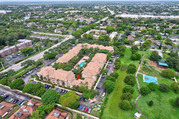 Aerial view of a residential complex with multiple buildings and a central swimming pool.