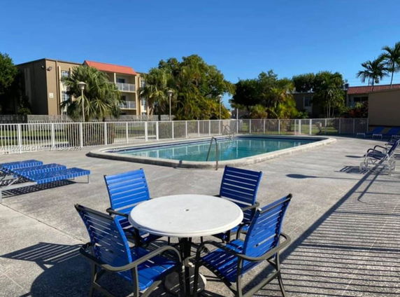 Outdoor swimming pool area with surrounding fence and lounge chairs.