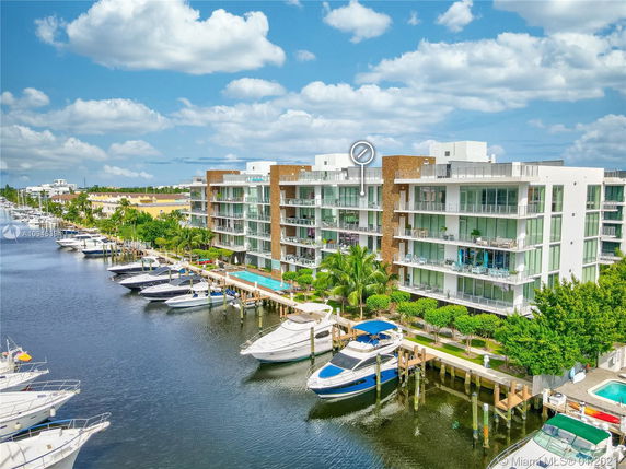View of modern waterfront apartment buildings with multiple floors and balconies overlooking a marina with boats docked.