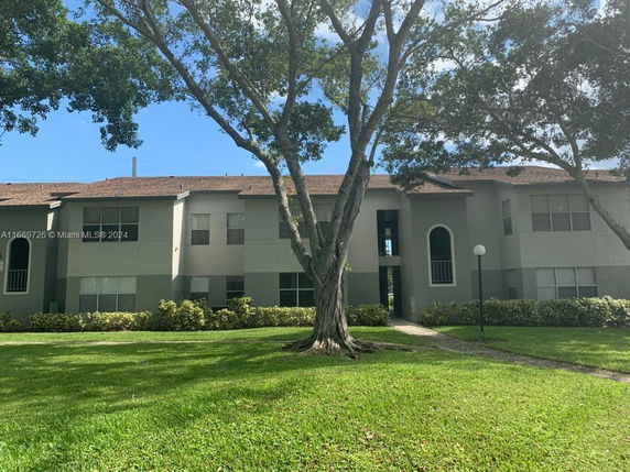 Front view of a two-story apartment building with green and beige exterior.