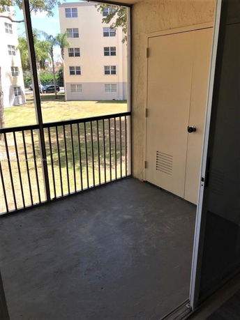 View from a screened porch looking out at a multi-story apartment building.
