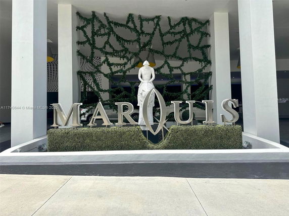 Exterior view of building entrance with decorative sign and statue.