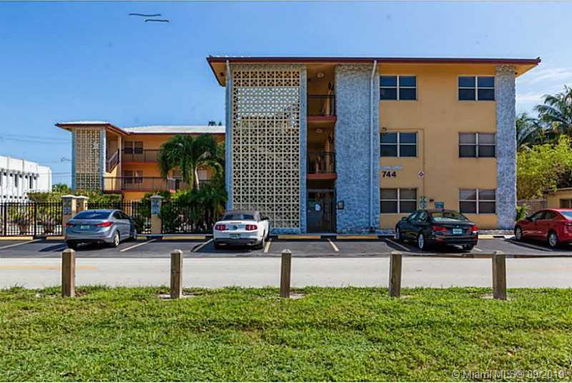 Front view of a three-story apartment building with a parking area.