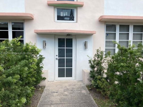 Front view of a building entrance with glass door and windows on either side.