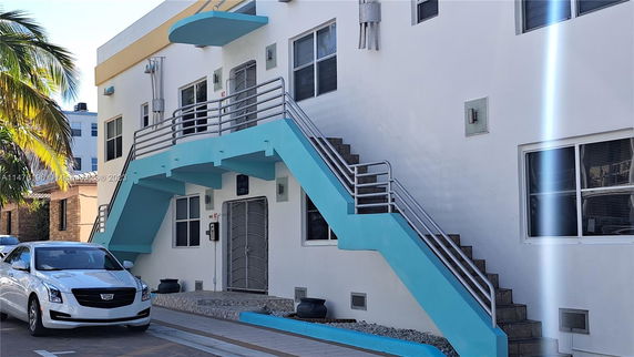Front view of a modern two-story building with exterior stairs and blue accents.