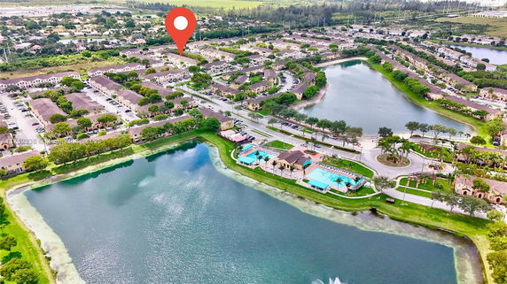 Wide aerial view of a residential neighborhood with multiple buildings, roads, and water bodies.