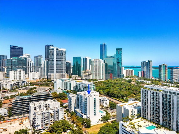 Aerial view of a cityscape with numerous high-rise buildings and a body of water in the background.